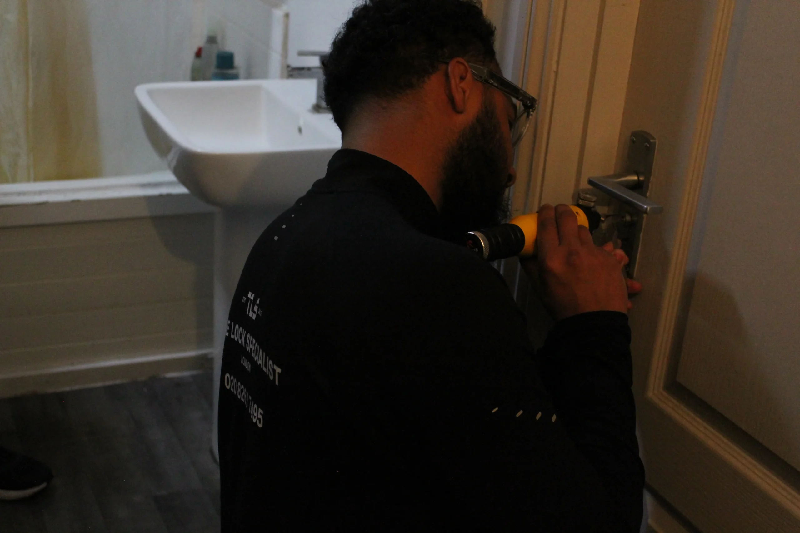 Locksmith engineer working on a front door lock during a night callout